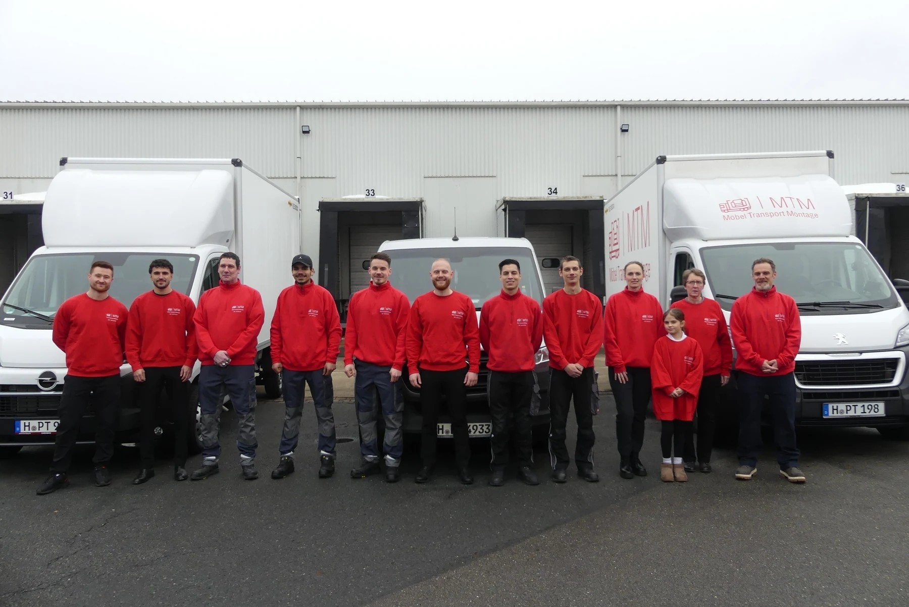 Gruppenfoto des MTM Teams vor mehreren Fahrzeugen.